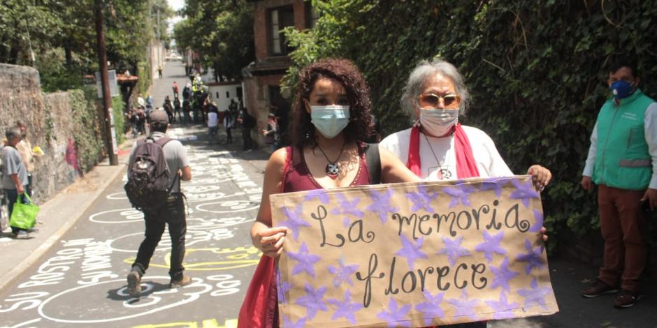Dos personas sostienen una pancarta frente a la casa de Luis Echeverría.