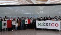 Mexicanos que fueron repatriados portan cubrebocas y sostienen banderas de México.