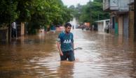 Un hombre camina en una calle inundada en Acayucan, Veracruz.