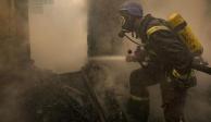 Un bombero ucraniano rocía agua dentro de una casa destruida por los bombardeos, en Kiev, Ucrania.