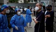 Trabajadores con trajes protectores dirigen a los residentes que hacen fila para hacerse pruebas de COVID-19, en medio de nuevas medidas para frenar el brote de la enfermedad en Shanghái, China