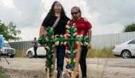 Personas&nbsp;lloran después de colocar cruces y velas en el lugar donde decenas de personas fueron encontradas muertas dentro de un tráiler en San Antonio, Texas.