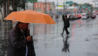 Un capitalino se resguarda de las fuertes lluvias en calles de la CDMX.