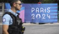 Un oficial de policía camina junto a un letrero de los Juegos Olímpicos de París 2024