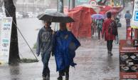 Personas en la calle con paraguas se cubren de la lluvia