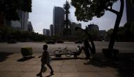 Una mujer camina en Paseo de la Reforma, a unos metros de donde descansa un ciclista, ayer.