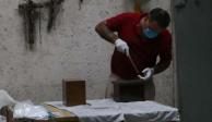 Personal funerario alista urnas con cenizas de víctimas de COVID.