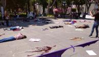 Mujeres simulan ser víctimas de feminicidio en protesta contra este delito en el Zócalo de Puebla.
