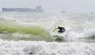 Un surfista se desplaza a orillas de la isla del Padre Sur el viernes 24 de julio de 2020 en medio de un mar picado debido a la tormenta tropical Hanna.