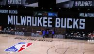 Los árbitros esperan de pie en una cancha vacía previo al inicio de un partido de los playoffs de la NBA entre el Magic de Orlando y los Bucks de Milwaukee, que ya no se desarrolló.