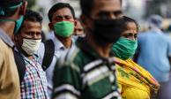 Pasajeros con mascarillas como precaución contra el coronavirus esperan a un autobús en Kolkata, India.