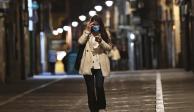 Una mujer con cubrebocas camina por una calle vacía de, Pamplona, en  el norte de España, ayer.