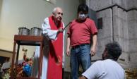 Padre bendice con agua a creyente en tiempos de COVID-19