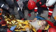 Rescatistas ayudan a la pequeña de cuatro años a salir de un edificio derrumbado.