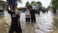 Los residentes caminan a través de las inundaciones cargando sus pertenencias en el vecindario de Suyapa, Honduras, el jueves 5 de noviembre de 2020.