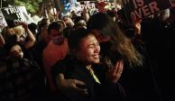 Las migrantes Angelique McKenna y Vivian Mora reaccionan al discurso del presidente electo, Joe Biden, en calles de Washington, ayer.