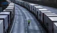 Un hombre camina junto a camiones estacionados en la autopista M20 cerca de Ashford, Gran Bretaña, ayer.