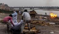 Tres hombres colocan un cuerpo en una pira funeraria a orillas del río Ganges en Uttar Pradesh, la semana pasada.
