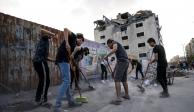 Palestinos limpian los escombros de edificios bombardeados por Israel.