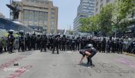 Una feminista realiza una pinta en el piso frente a policías capitalinos equipados con escudos antimotines.