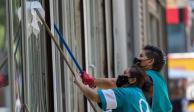 Un par de mujeres trabajan limpiando los cristales de un edificio en Paseo de la Reforma