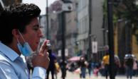Un hombre fuma un cigarro sobre la calle de Madero.