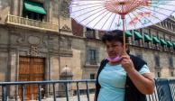 COVID-19: Una mujer con cubrebocas en la barbilla camina frente a Palacio Nacional