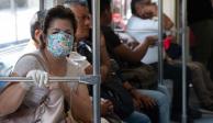 COVID-19: Una mujer se protege del coronavirus con cubrebocas y guante mientras viaja en el transporte público, no así otros usuarios que van junto a ella
