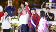 El presidente Daniel Ortega con el brazo levantado por el líder de la Asamblea General, Gustavo Porras, y su esposa, la vicepresidenta Rosario Murillo.