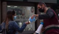 Un trabajador del gobierno capitalino reparte gel antibacterial en las inmediaciones del Centro Histórico