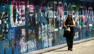 Una mujer camina cerca de las vallas que terminaron con pintas, en el Centro Histórico de la Ciudad de México, ayer.