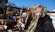 Una mujer inspecciona sus pertenencias en las ruinas de su casa que fue atacada en un ataque militar, en medio de la invasión rusa en Ucrania, en Kiev.