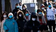 Gente caminando por las calles de China mientras usa cubrebocas por la pandemia de COVID-19