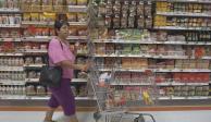 En la imagen, una mujer con su carro de compras en un supermercado