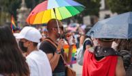 Un joven con una sombrilla multicolor toma una bebida durante la Marcha LGBT+ de este sábado en la CDMX