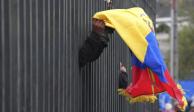 Un manifestante indígena lleva una bandera ecuatoriana dentro de la Casa de la Cultura en Quito mientras policías fuerzan a los manifestantes a quedarse adentro durante una protesta contra el gobierno del presidente Guillermo Lasso el 24 de junio del 2022
