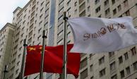 La bandera del promotor inmobiliario Shimao Group ondea junto a una bandera china en Shanghai, China.