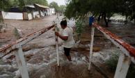 Familiar de uno de los mineros atrapados en Sabinas cruza una corriente de agua extraída del sitio.