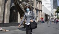 Una mujer camina por la calle con un cubrebocas para protegerse de enfermedades respiratorias