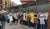 Integrantes del colectivo Voz de los desaparecidos de Puebla colocan fotografías de víctimas en vallas metálicas instaladas en Palacio Nacional este lunes