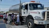 Un grupo de personas espera su turno para llenar sus cubetas de agua en Nuevo León