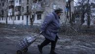 Una mujer camina a un centro de distribución de ayuda humanitaria frente a una vivienda dañada por los ataques rusos en Kupiansk, en la región de Járkiv, Ucrania, el miércoles 26 de diciembre de 2022.