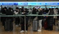 Pasajeros en Corea del Sur esperan en fila para abordar un avión hacia China, ayer.