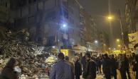 Afectados se reúnen frente a un edificio colapsado por si escuchan a posibles víctimas.