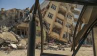 Un edifico destruido se ve inclinado sobre una casa cercana en tras una serie de sismos en Samandag, en el sur de Turquía.