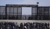 Migrantes que cruzaron la frontera desde México hacia Estados Unidos esperan a un costado del muro fronterizo en donde agentes de la Patrulla Fronteriza de Estados Unidos montan guardia, el 30 de marzo de 2023, en una imagen tomada desde Cuidad Juárez, México.