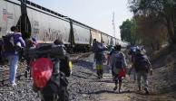 Migrantes caminan junto a un tren con dirección al norte, esperando poder subirse a él, en Huehuetoca, México, el viernes 12 de mayo de 2023.