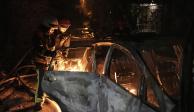Socorristas tratan de apagar un auto que se incendió por la caída de escombros tras un ataque aéreo ruso en el distrito de Pecherskyi, en Kiev, Ucrania, el martes 30 de mayo de 2023.
