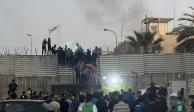 Manifestantes trepan un muro en la embajada sueca de Bagdad, el jueves 20 de julio de 2023. Manifestantes airados por la quema de un ejemplar del Corán irrumpieron en la embajada sueca en Bagdad, donde provocaron un pequeño incendio.