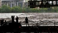 Varias personas observan el desbordamiento del río Yongding tras las fuertes lluvias caídas en Pekín, China, el 31 de julio de 2023.